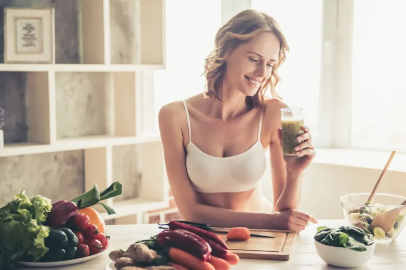 Woman with smoothie and fruits surrounding