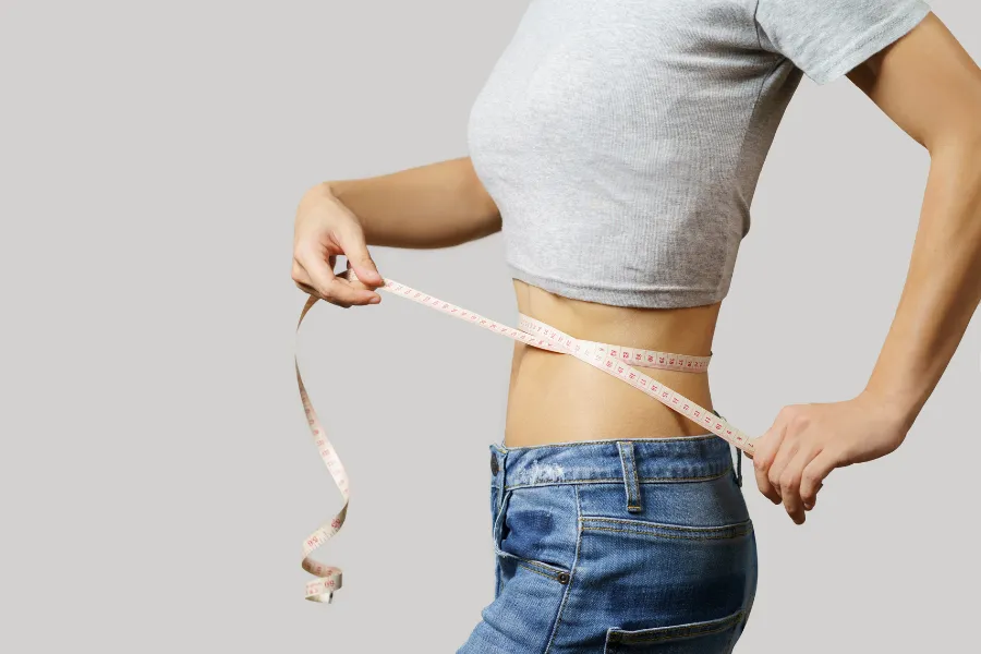 Woman measuring waist with a tape measure