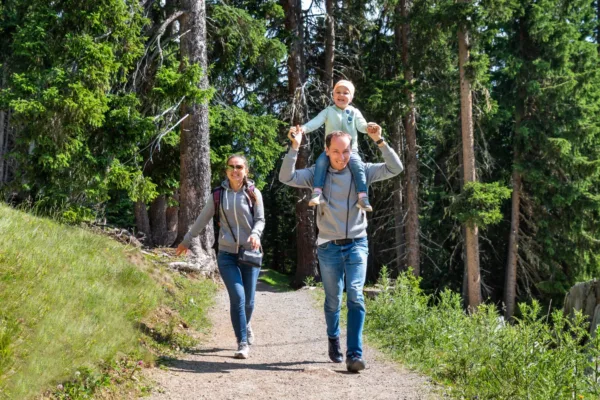 Couple with kid on dads shoulders walking through a trail