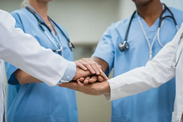 Doctors putting hands in, teamwork