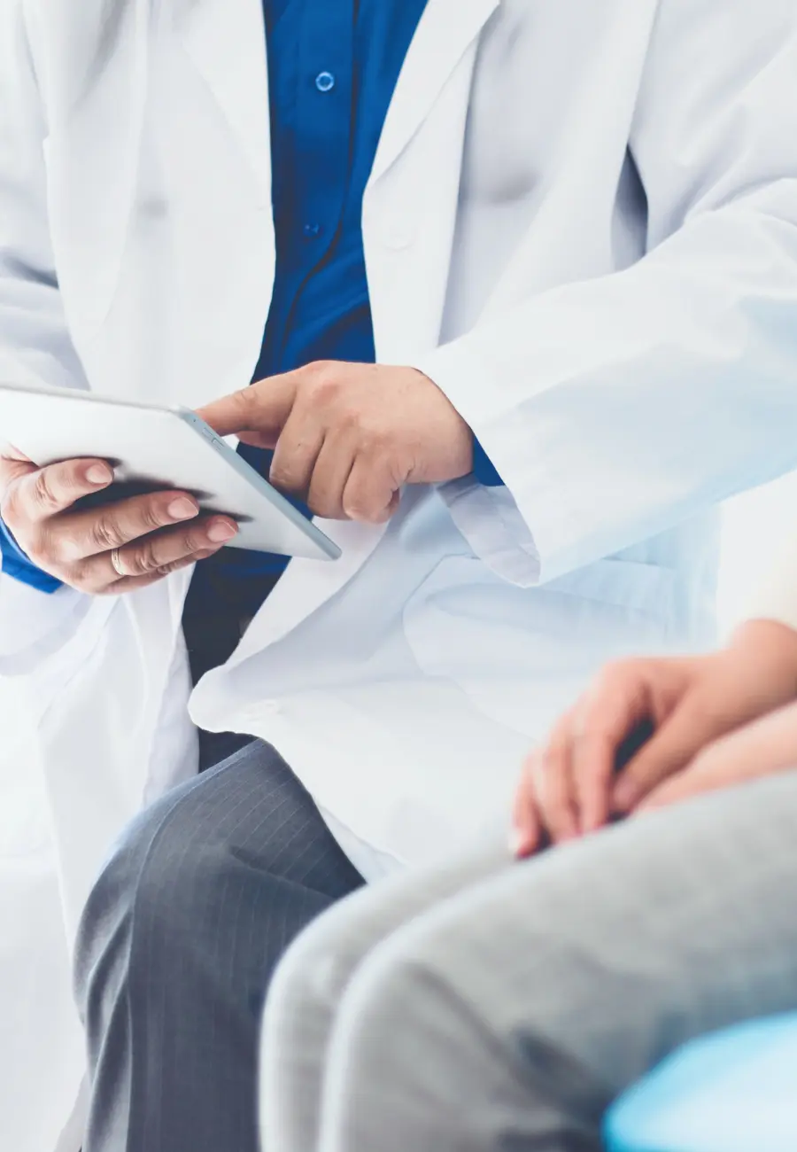 Doctor sitting with patient and closeup of hands on tablet