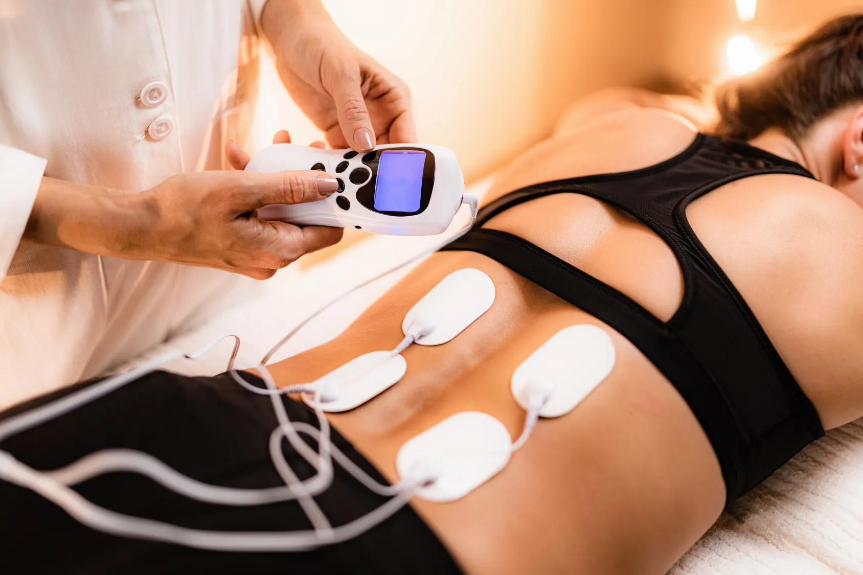 Patient receiving electrotherapy treatment on the lower back to relieve pain.