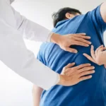 Doctor assessing a patient’s lower back during a physical exam.
